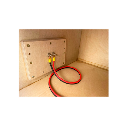 A wooden board with two bolts holding red and black wires, attached to a plywood wall—possibly part of the Basshead Supply American Bass Dual 15" King Ported Enclosure—designed for electrical or speaker connections inside this custom subwoofer enclosure.
